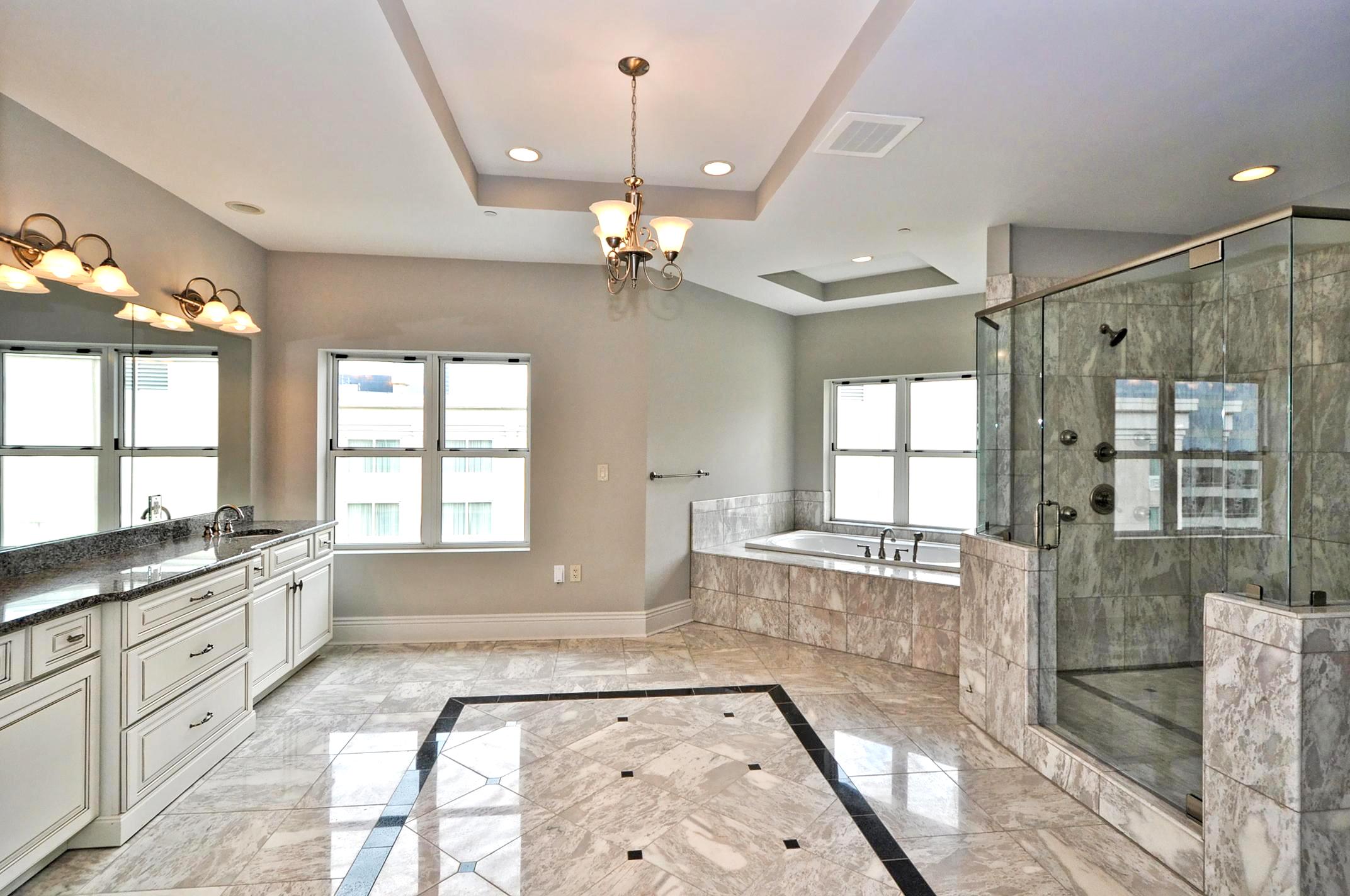 Spacious bathroom remodel with dual vanity, soaking tub, and glass tile shower