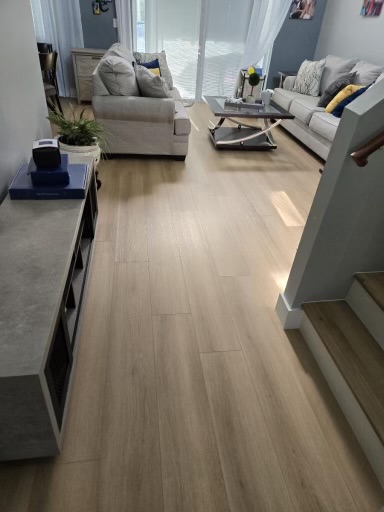 Living room with light wood-look flooring near a staircase